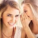 Beautiful smiling as another woman whispering unto her ears